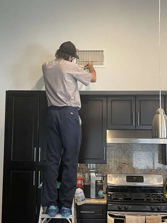 Technician inspecting an air vent during HVAC service in Page